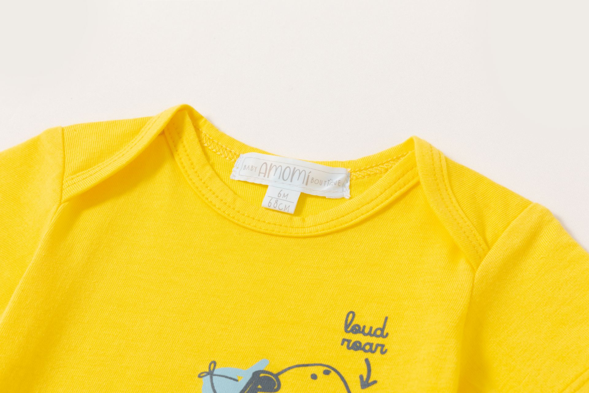 0021067_bodies-3-a-24-meses - Da-Da Kids Close-up of a bright yellow toddler T-shirt collar with a white size tag reading 6M 68CM.