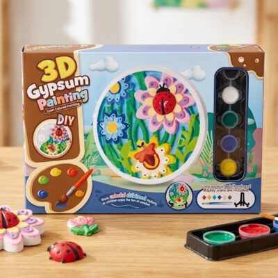 232042bf-0027-497d-ae2f-09ceeb14dd68 - Da-Da Kids DIY 3D gypsum painting kit box on a table with paints, brushes, and painted clay flowers.
