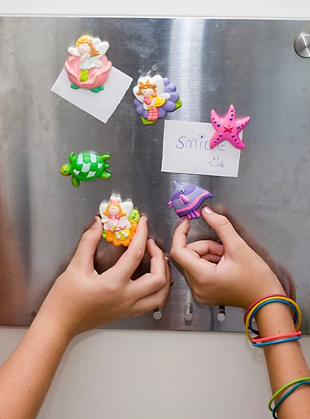 mould-paint-craft-kit-sealife~4893156035110_03c_MP - Da-Da Kids Children's hands place colorful clay sea creatures—a mermaid, turtle, starfish, and fish—on a metal board with note cards that say 'smile'.